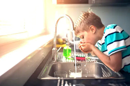 Junge trink Leitungswasser aus dem Wasserhahn