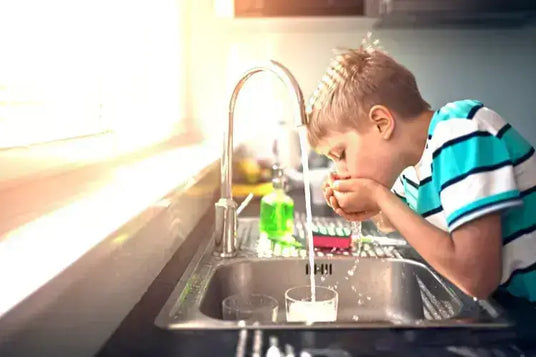 Junge trink Leitungswasser aus dem Wasserhahn