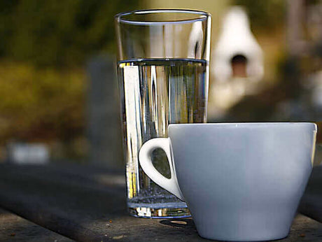 Ein Glas Wasser hinter einer Tasse in einem Biergarten