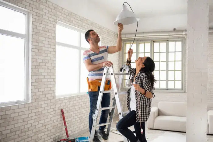 Paar bringt Lampe an der Decke an